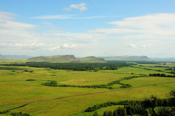 une vallée pittoresque sans fin et une chaîne de hautes collines sous un ciel d’été nuageux. - grass area hill sky mountain range photos et images de collection