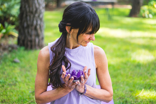 Mid adult woman holding holding a purple glass lotus. Yoga and meditation concept.