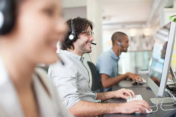 Photo of Business people with headsets working at computers in office