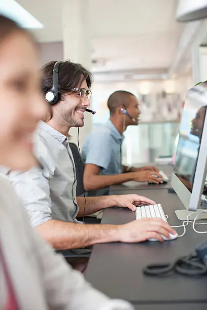 Photo of Business people with headsets working at computers in office
