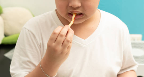 kind isst pommes frites im zimmer - child obesity stock-fotos und bilder