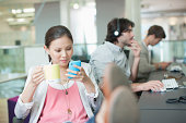 Businesswoman drinking coffee and text messaging with feet up in office