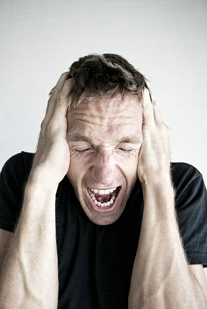 istock Man Screams Holding His Head in Black T-Shirt 170153886