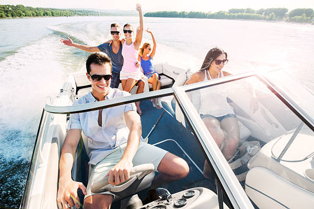 Cheerful group of young people enjoying in speedboat ride. Group of young people sitting in a speedboat and enjoying the ride.    fast boat stock pictures, royalty-free photos & images