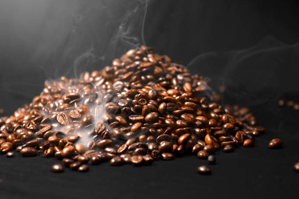 Closeup view of fresh roasted coffee beans with smoke in the background