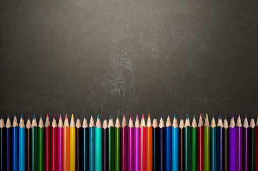 The row of colored pencils on a colored background. World Teacher Day concept