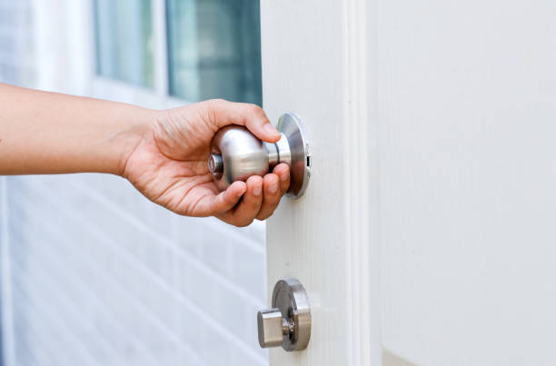 istock Hand opening Modern white door with chrome metal handle. Elements of interior, close up, To open the door, security, entrance concept. 1701577459