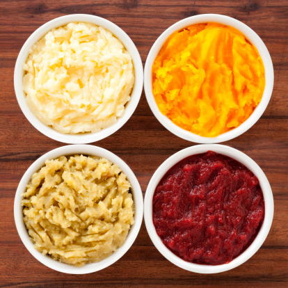 Top view of four bowls containing variety of purees (potato, squash, sweet potato and beet)
