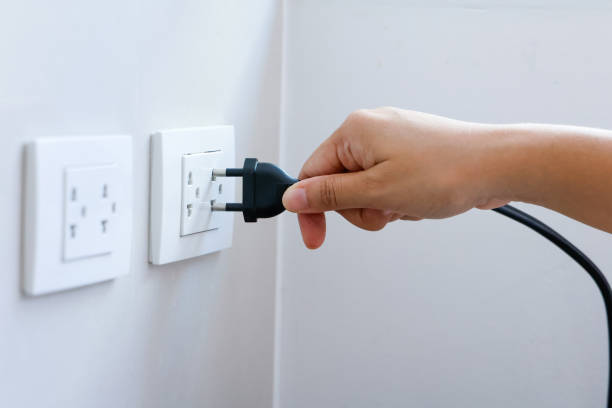 istock Hand holding plug connect to a power plug into a electrical outlet on a wall, power outlet socket, power saving concept, energy saving, energy conservation. 1701577996