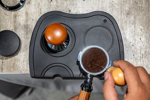 Barista hand holding portafilter with fresh ground coffee. Make espresso coffee