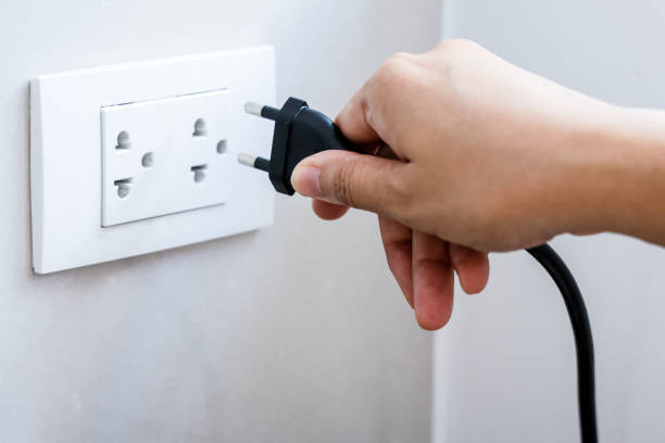 istock Hand holding plug connect to a power plug into a electrical outlet on a wall, power outlet socket, power saving concept, energy saving, energy conservation. 1701578523