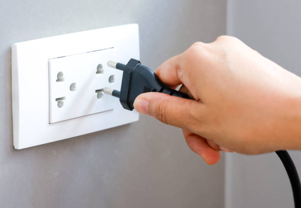 spina di tenuta manuale collegare a una spina di alimentazione in una presa elettrica su una parete, presa di corrente, concetto di risparmio energetico, risparmio energetico, risparmio energetico. - electric plug outlet human hand electricity foto e immagini stock