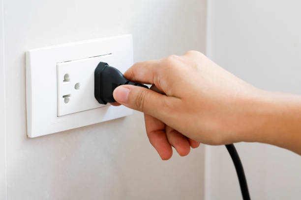 istock Hand holding plug connect to a power plug into a electrical outlet on a wall, power outlet socket, power saving concept, energy saving, energy conservation. 1701578545