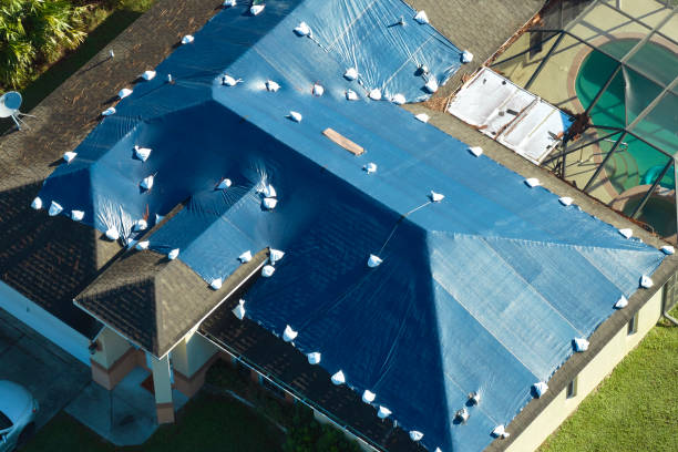 istock Hurricane Ian damaged house rooftop covered with protective plastic tarp against rain water leaking until replacement of asphalt shingles. Aftermath of natural disaster 1701596561