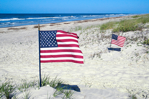 Two American Flags blow in the wind on an isolated beach in South Carolina. 