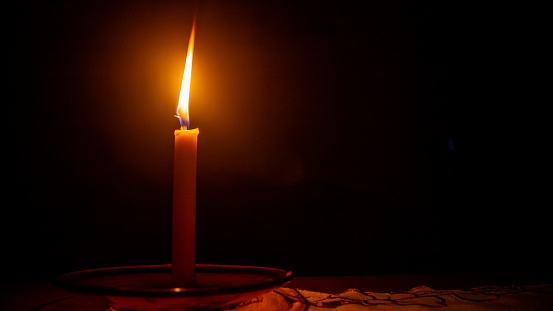 a burning candle against a dark background