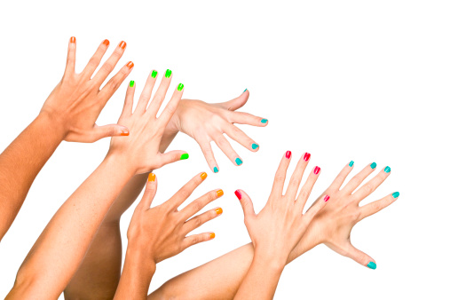 Group of raised multiethnics female hands with colored manicure. Isolated on white with clipping path.