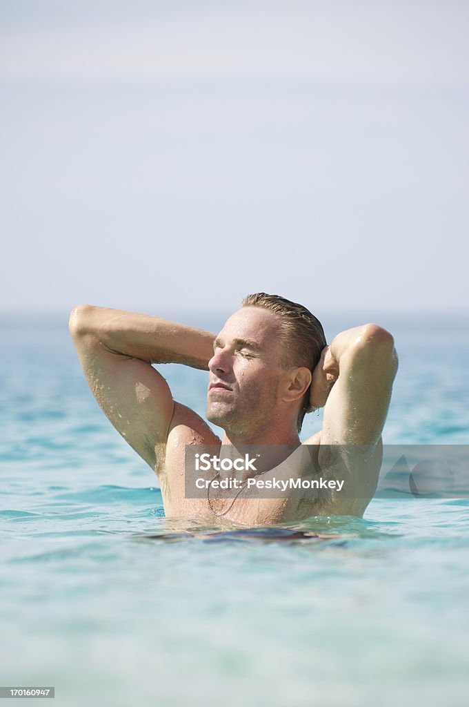 Hombre s'encuentra en la Sea contemplar los brazos de sol detrás de la cabeza - Foto de stock de Adulto libre de derechos
