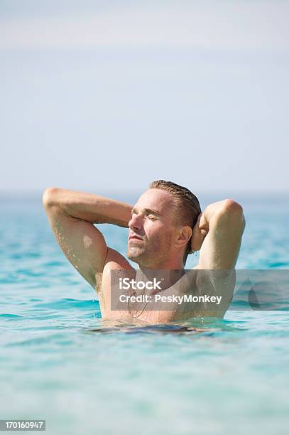 Hombre Sencuentra En La Sea Contemplar Los Brazos De Sol Detrás De La Cabeza Foto de stock y más banco de imágenes de Adulto