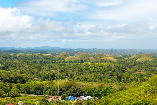 Amazingly shaped Chocolate hills on the distance on sunny day on Bohol island, Philippines. Dramatic cloudy sky on a sunny day, copy space for text