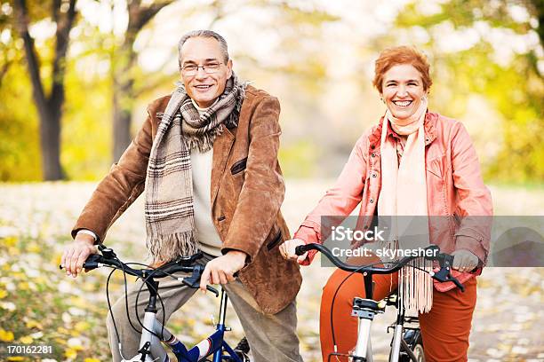 Adulto In Età Matura Coppia Biciclette Equitazione Nel Parco - Fotografie stock e altre immagini di Abbigliamento casual