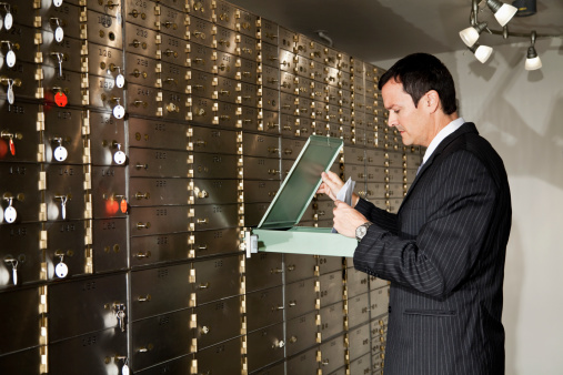 Businessman, 40s, putting documents in safety deposit box.