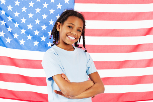 Happy young girl with American flag in the background.   