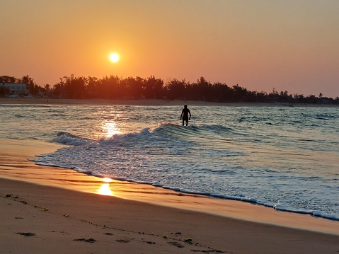 Man surfing with orange sun is mozambique