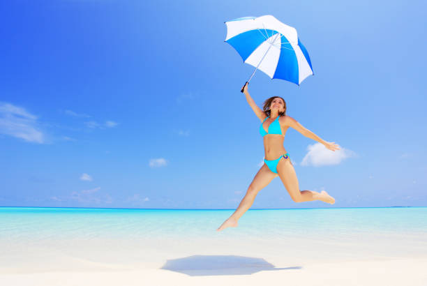 istock Young woman jumping with umbrella on exotic beach. 170169376