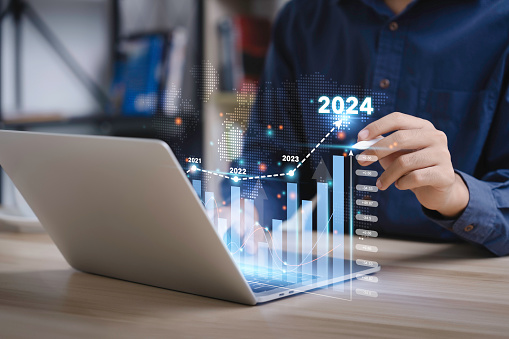 Businessman analyzes the graph of trend market growth in 2024 and plans business growth and profit increase in the year 2024. plan finances of the business