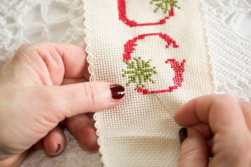Cross Stitch with Hands Holding Needle and Thread, making letter G with a snowflake