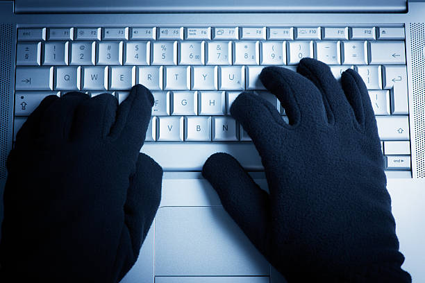 A person wearing gloves while on the computer  stock photo