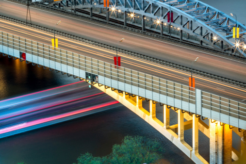 Long exposure with motion blur of cars moving over Andreevsky bridge and water-bus sailing under Andreevsky bridge, Russia. View from the Russian Academy of Sciences headquarters building