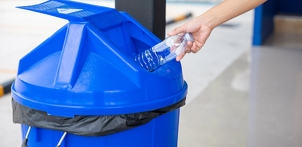 Close up woman hand throwing empty plastic water bottle into recycling bin, female throwing empty bottle to trash, Recycle rubbish, save the world and environment care