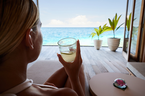 Close up of relaxed woman drinking juice on a patio by the sea. Copy space.