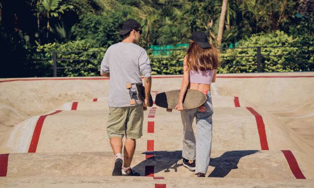 joven pareja feliz con patinetas disfrutan del longboard en el skatepark - 18827 fotografías e imágenes de stock