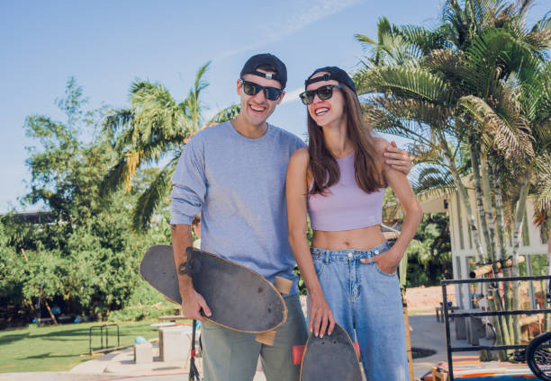 un jeune couple heureux avec des planches à roulettes profite du longboard au skatepark - 18813 photos et images de collection