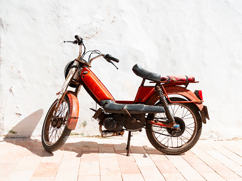 Old red moped in front of a white wall in Rabat, Morocco. Africa.