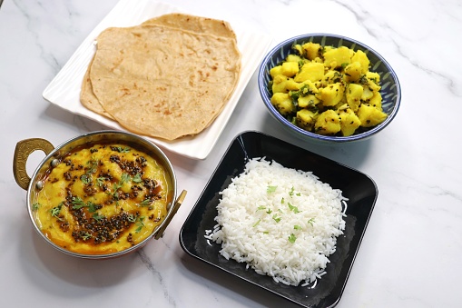 Indian simple homecooked meal aloo ki sabzi, roti, dal, chawal. Wholesome comfort food. vegetarian thali or Indian food with lentils, potato curry, rice and flat bread. copy space