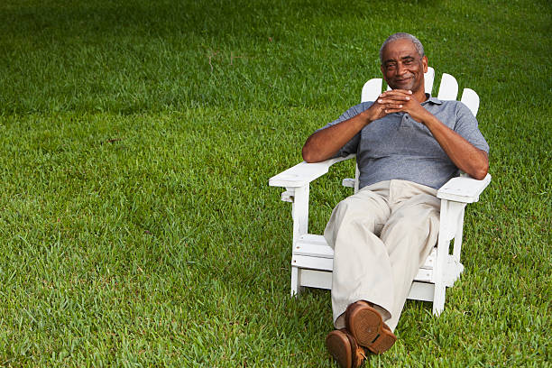 senior afro americano uomo seduto nella sedia adirondack - adirondack chair foto e immagini stock