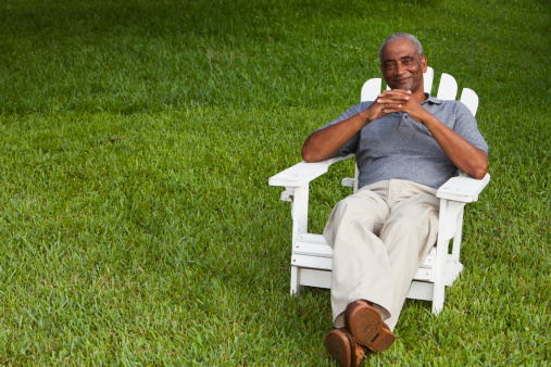 Senior African American man (60s) sitting in adirondack chair.