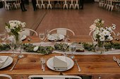 Classic long dining table decorated with elegant floral centerpieces and napkins foe the wedding