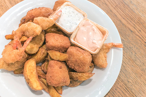 Indulge in the crispy goodness of fish nuggets, garlic prawns, and potato wedges served with a choice of delectable dipping sauces for a delightful meal.