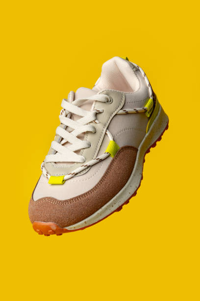 istock Beige sport running shoes on yellow studio background 1701782111