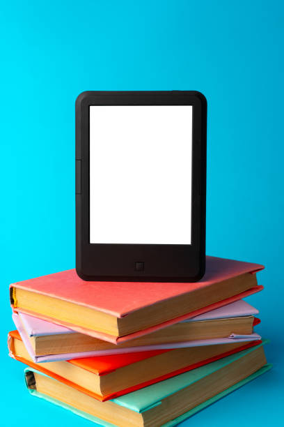 istock Modern e-book on stack of hardcover books on blue background 1701786980