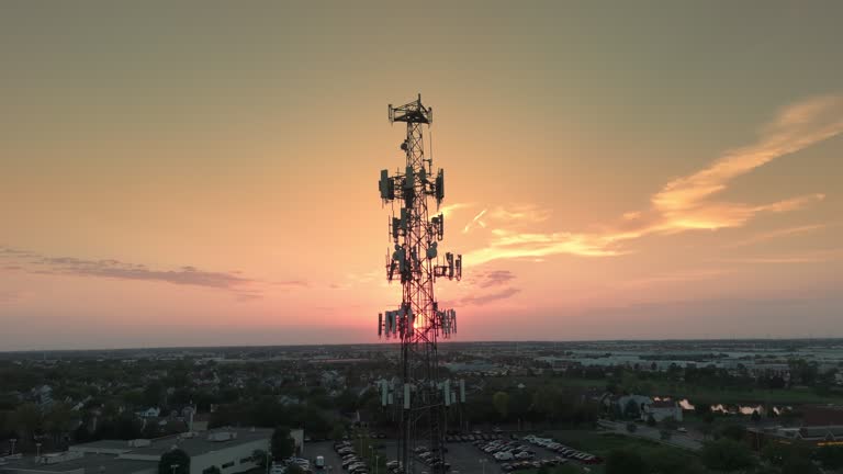 Television or radio telephone tower in a cityscape at sunset time. Wide drone shot footage