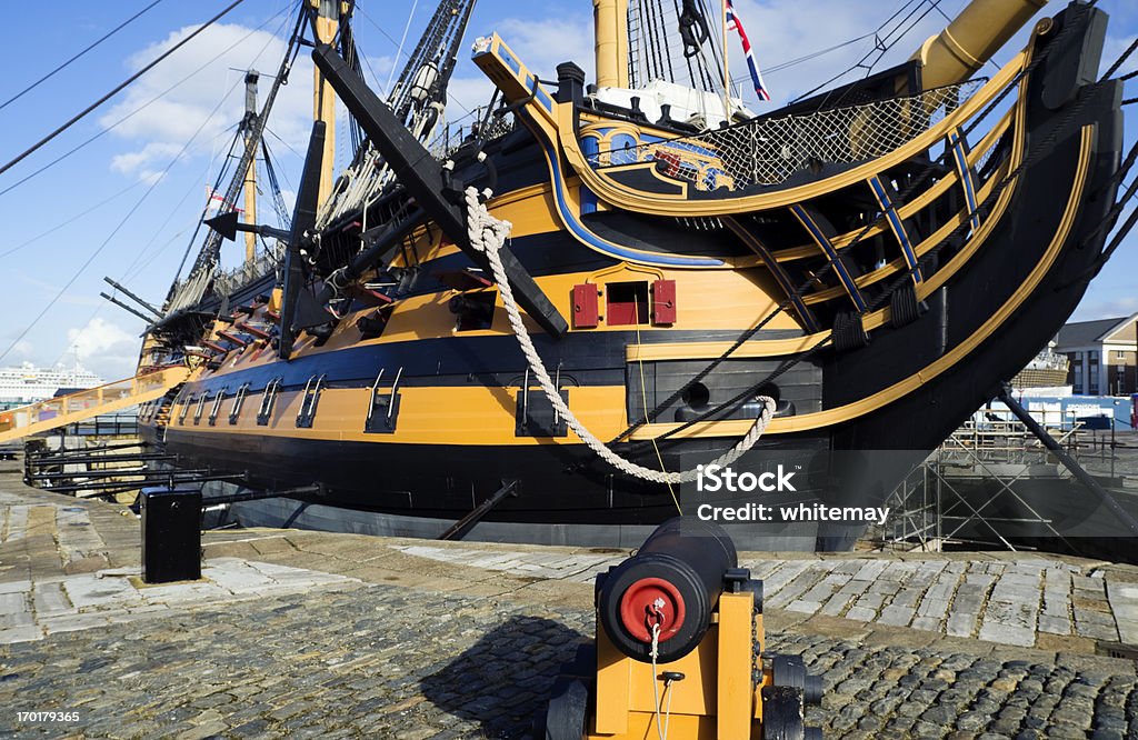 HMS Victory under repairs A cannon standing beside Lord Nelson's flagship, HMS Victory, in dry dock at Portsmouth. The Victory is currently undergoing extensive repair and restoration, so the masts have been taken down and there is scaffolding around the hull. Portsmouth - England Stock Photo