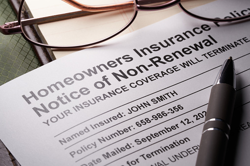 Non-Renewal home owners insurance letter document with glasses and pen