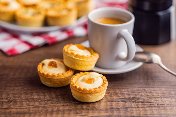 Sweet tarlets. Tasty mini tarts. Mini pie with cream and coffee cup  on the kitchen table.