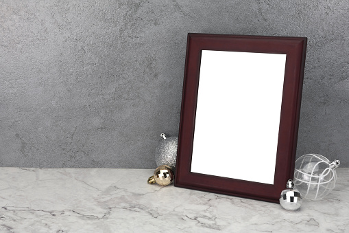 Blank frame with christmas balls decorations on marble table. Mock up for your photo or text. Frame mockup.